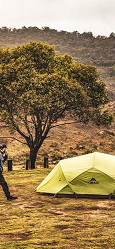 Two men walk past a green tent at Blue Waterholes campground, Kosciuszko National Park. Photo: