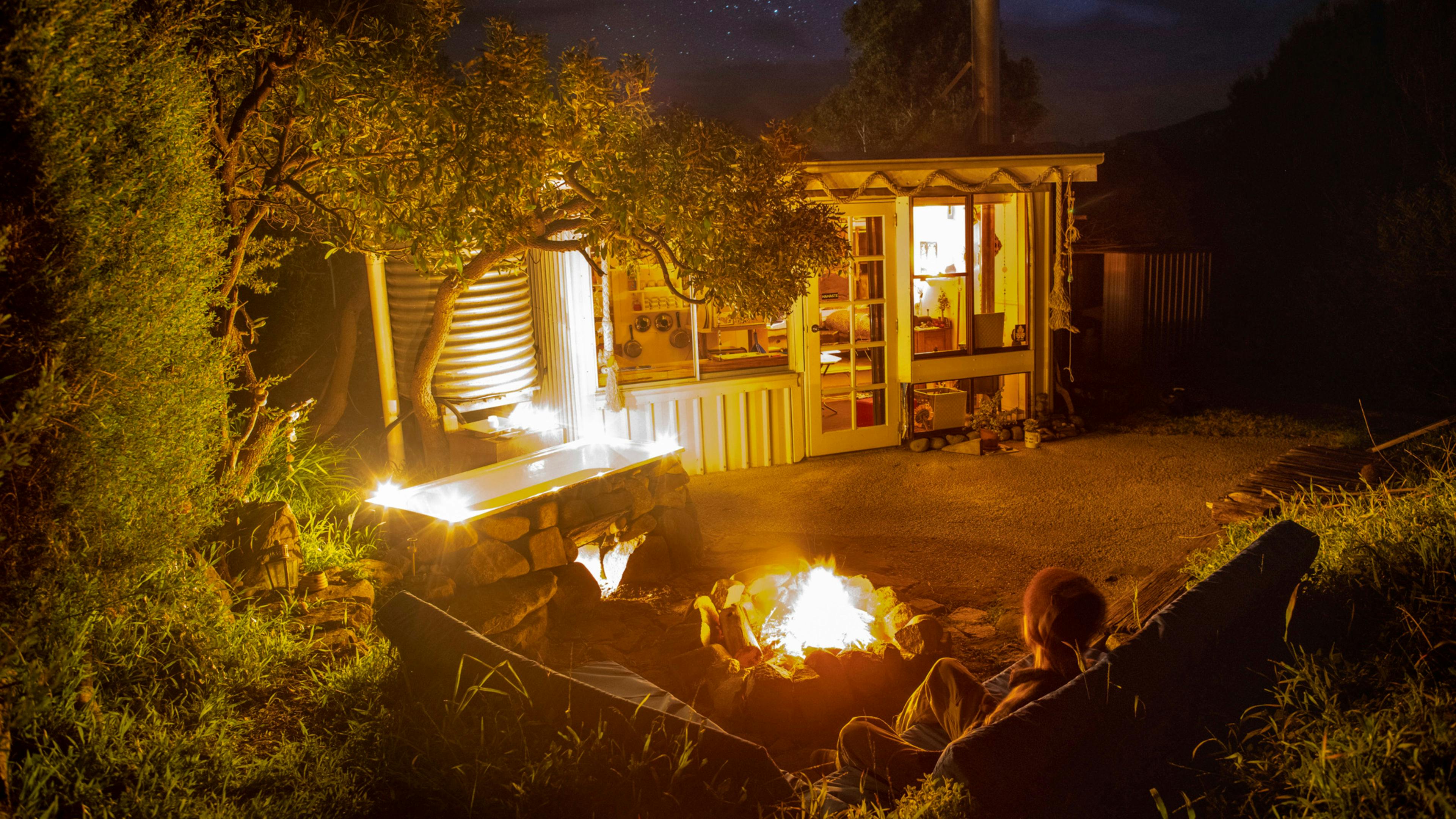 Sit on the outdoor lounge waiting for the fire under the bath to heat the water.  The heated rocks keep the water warm.      