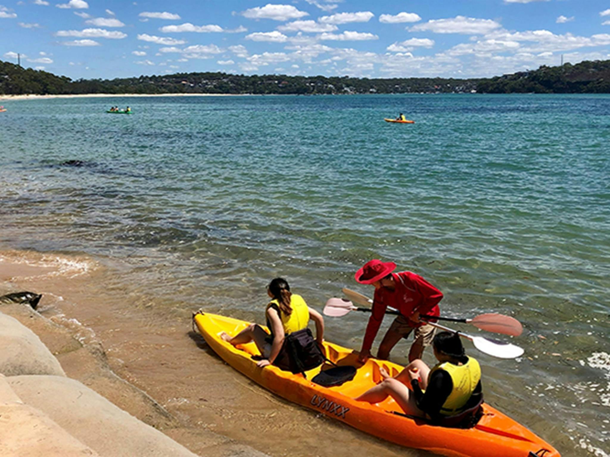 People being helped into a kayak in ocean, at Bonnie Vale picnic area. Photo: OEH/Natasha Webb