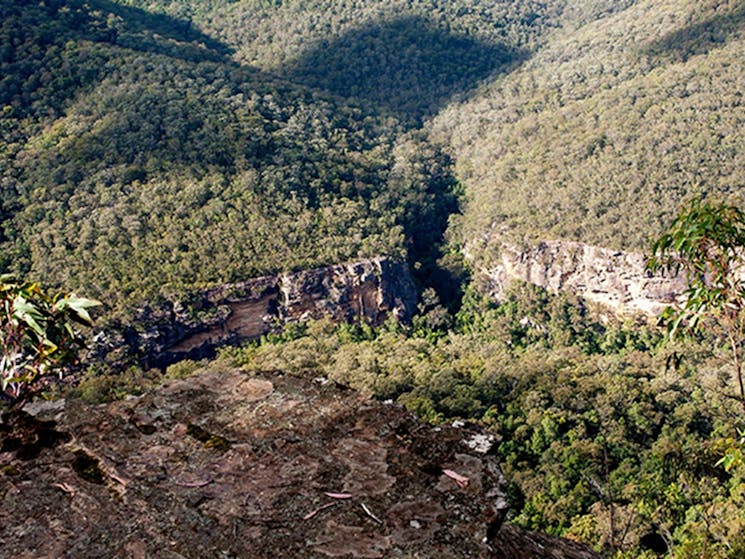 View over rocky ledge at Beauchamps Cliffs lookout to rugged cliffs and untracked bushland in Morton