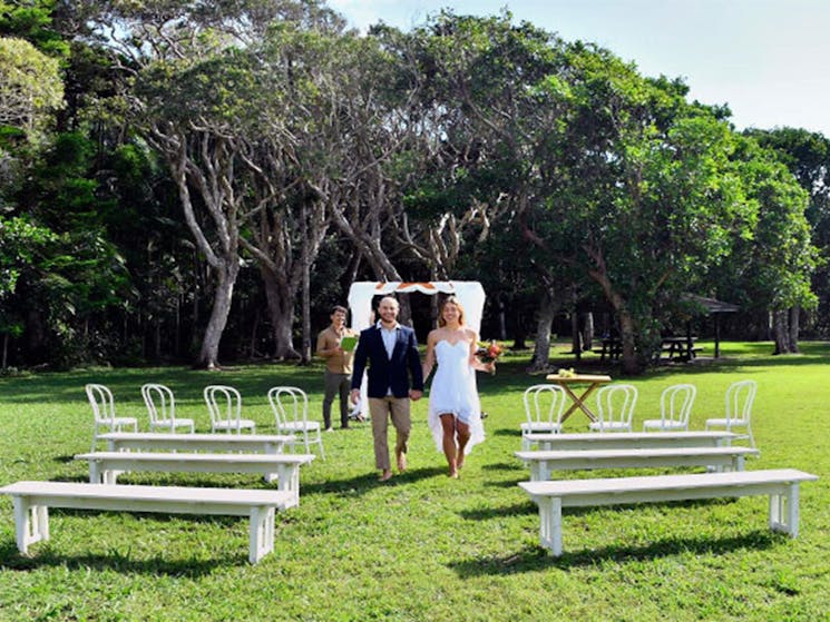 A couple walking down the aisle after their wedding ceremony at Broken Head lawn. Photo: Fiora Sacco