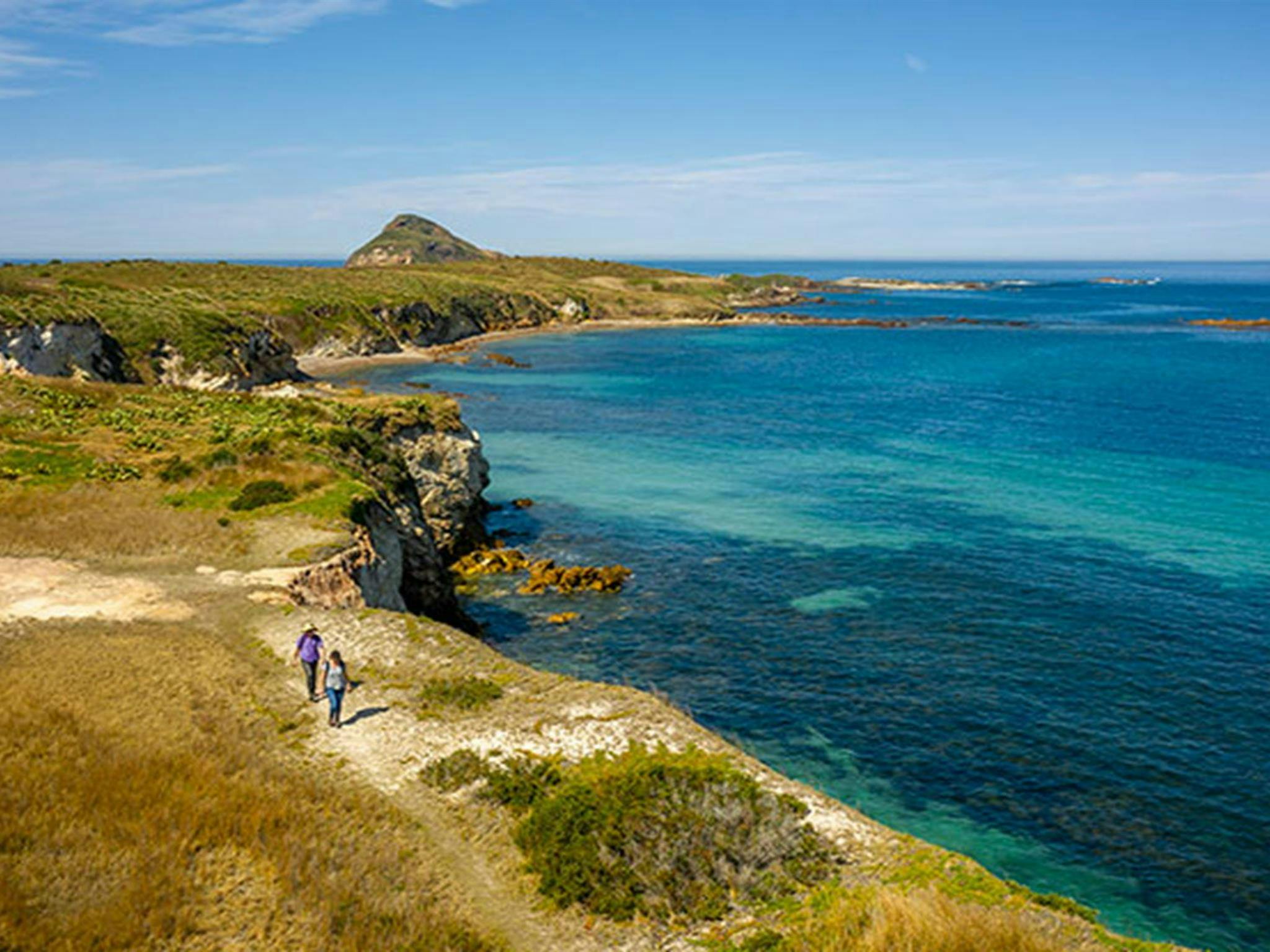 2 people walking near Coal Shaft Bay lookout on Broughton Island. Photo: John Spencer/DPIE