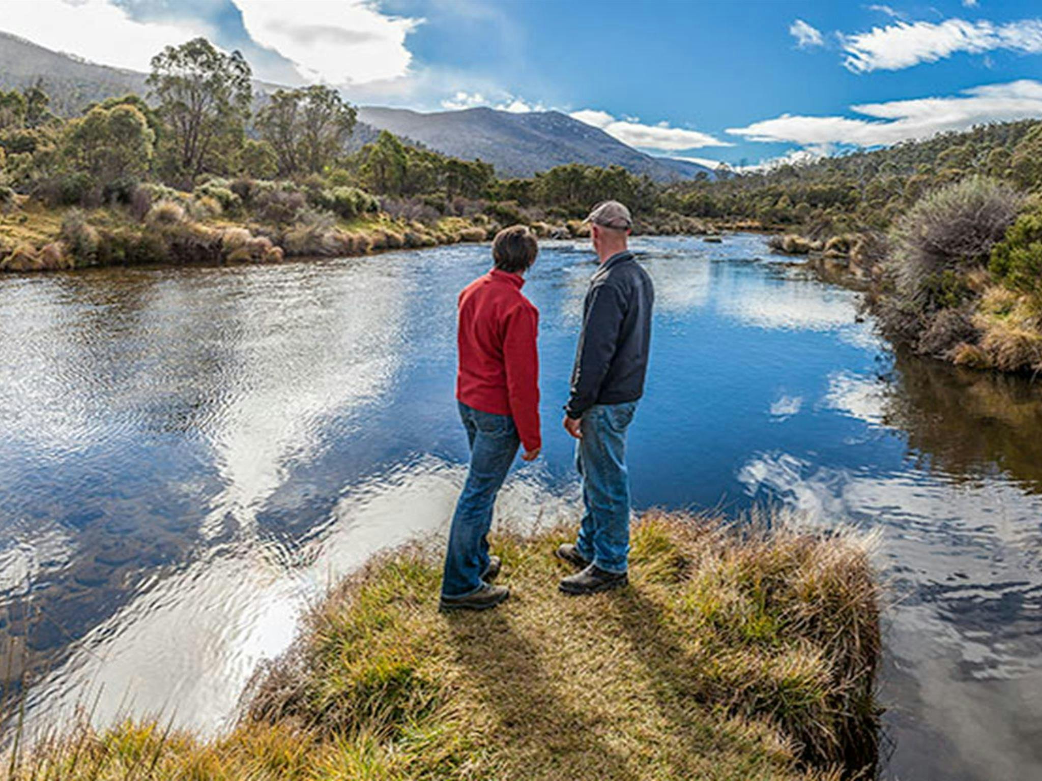 A man and woman stand beside the Thredbo River near Bullocks Hut, Kosciuszko National Park. Photo:
