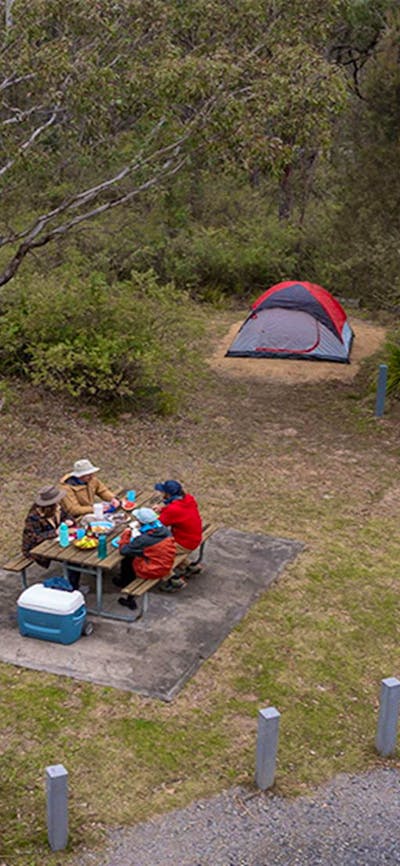 A group of campers eating at the picnic table next to their campsite at Bungonia campground. Photo: