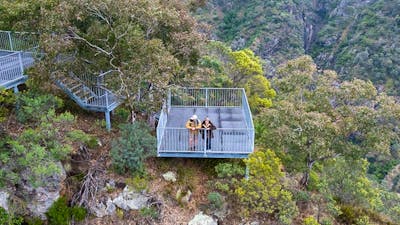 Two visitors look down into the bush and cliff face at Adams lookout and picnic area, Bungonia