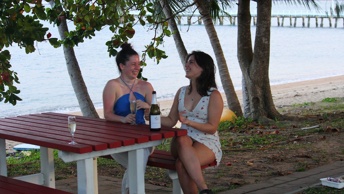 Beachside picnic: Two friends sipping bubbles