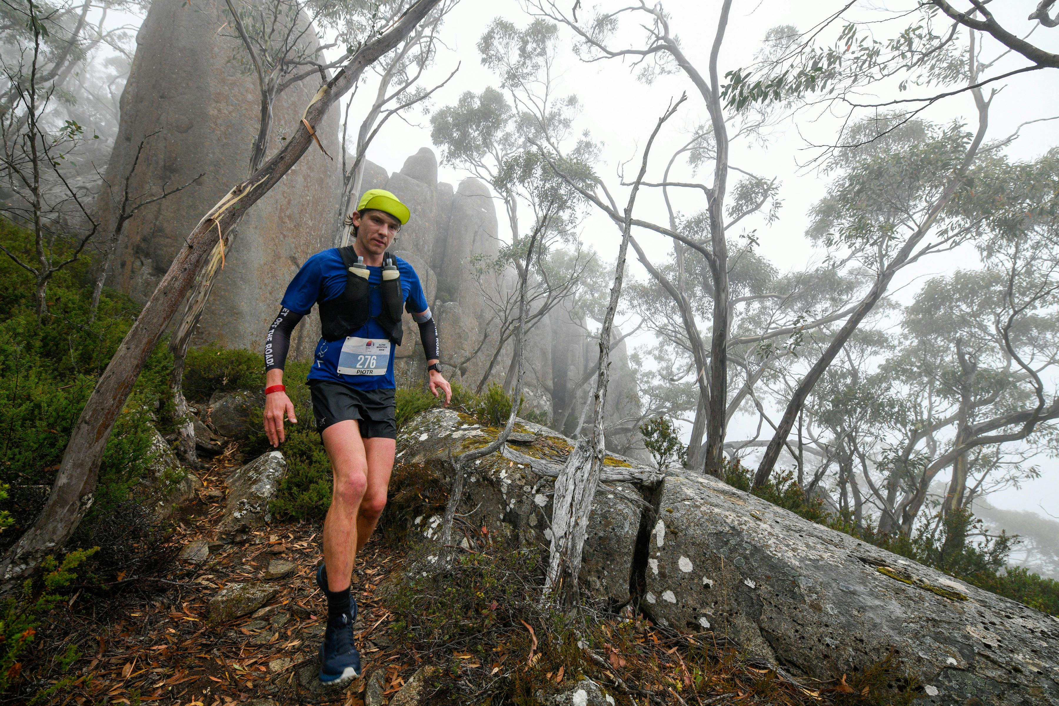 A malae runner passes rocks, towering above, as they pass through mist