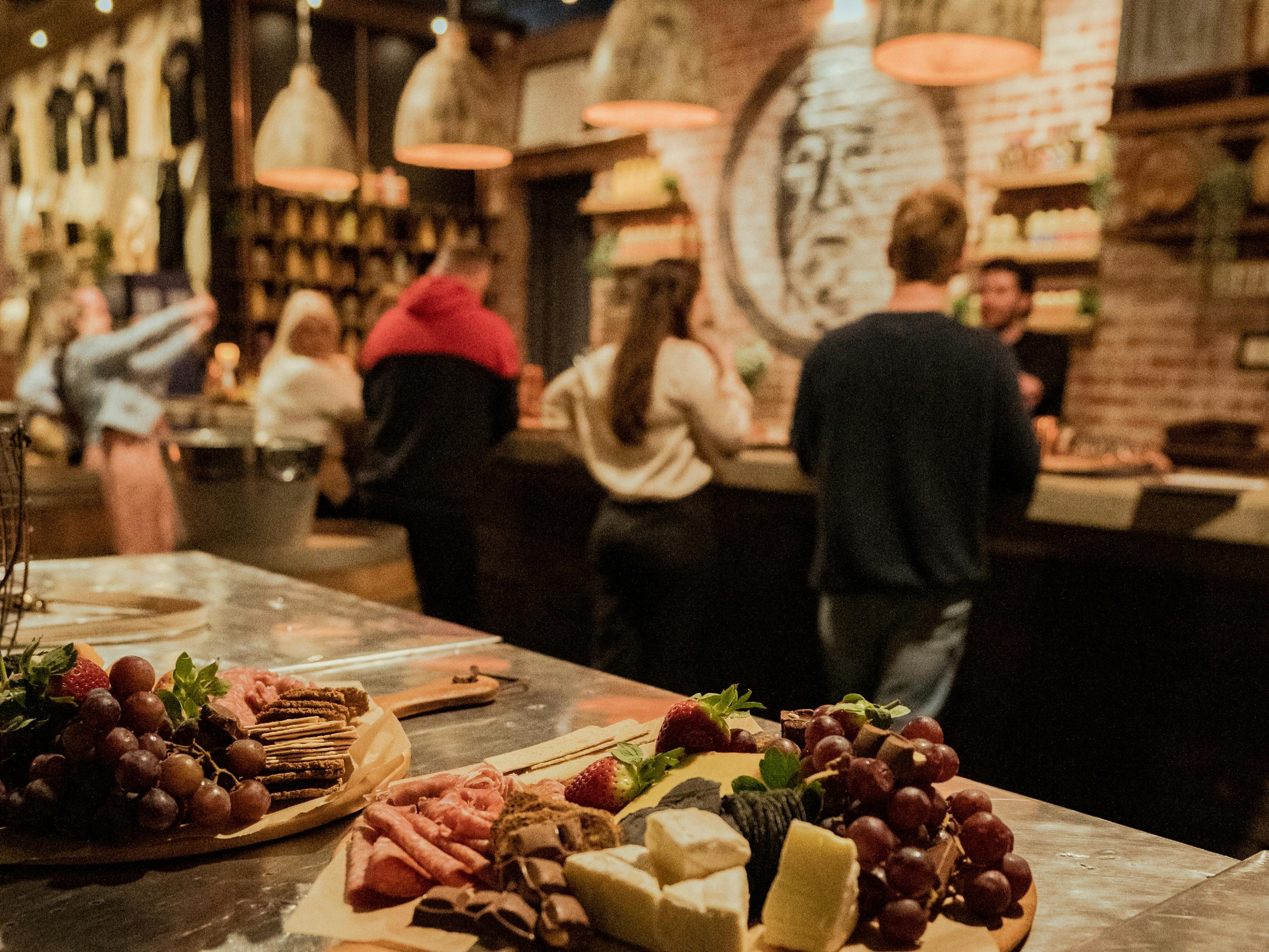 Cheeseboards on a table facing our Tasting Room bar as people sit and enjoy a cocktail class.