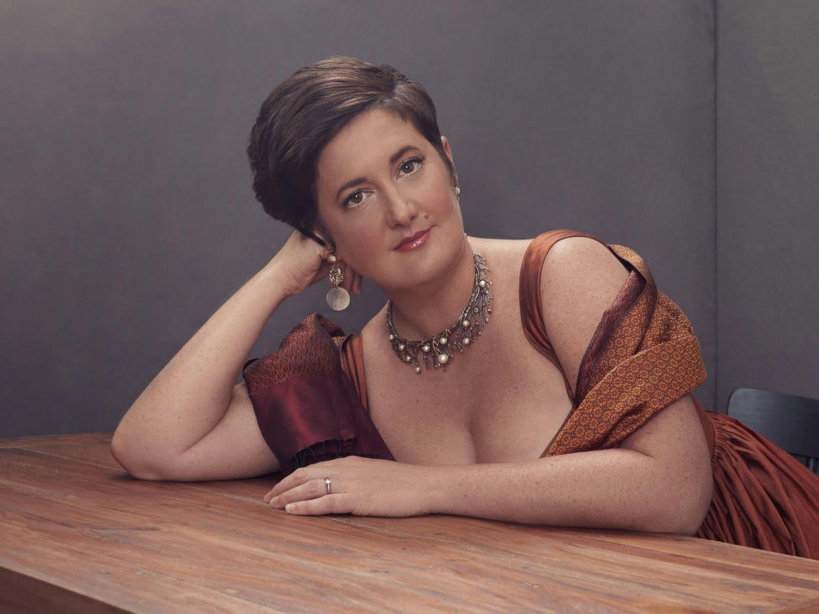 Female opera singer leaning on table.