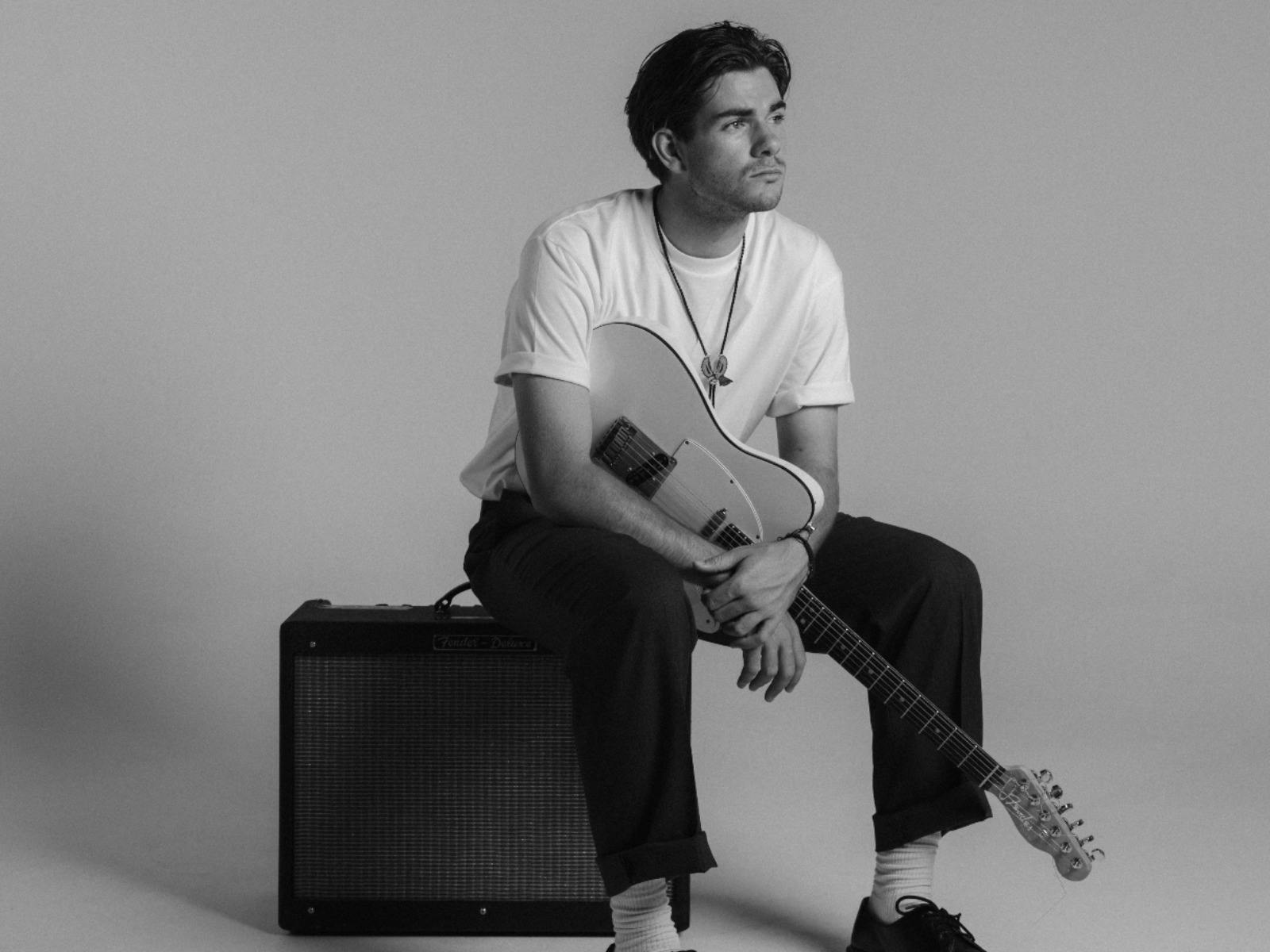 Flynn sitting on an Amp with guitar slung on his shoulder