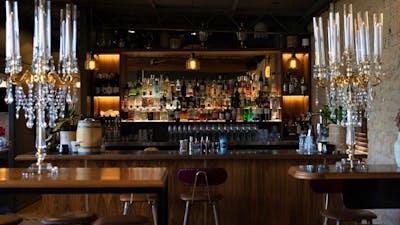 Bar lined with many bottles of alcohol and standing candlestick holders