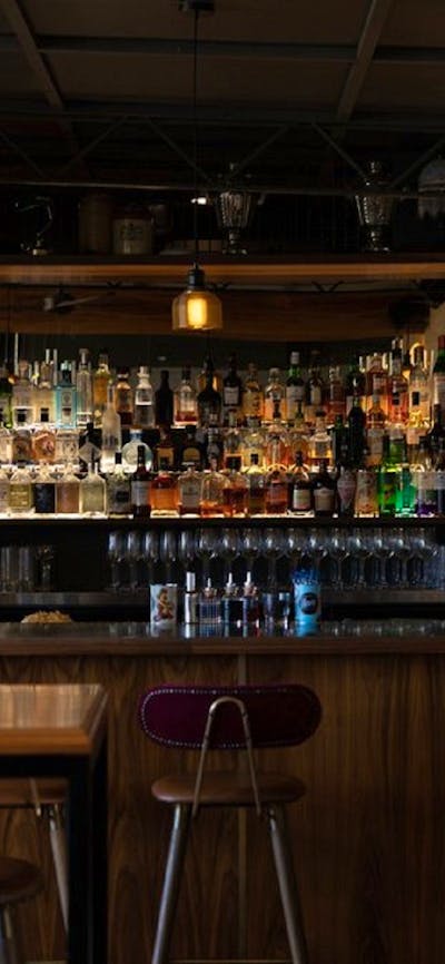 Bar lined with many bottles of alcohol and standing candlestick holders