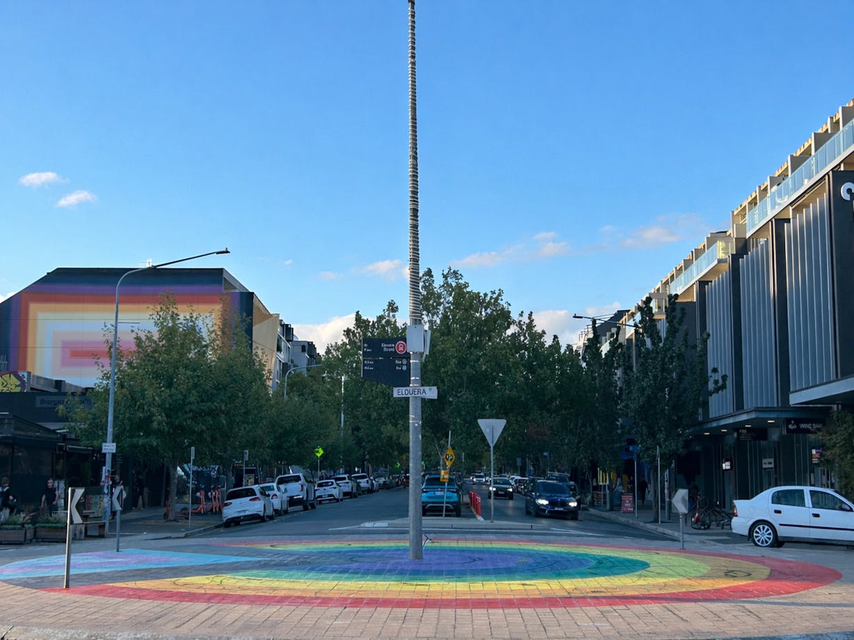 a roundabout with colourful concentric circles pained on the ground in rainbow colours