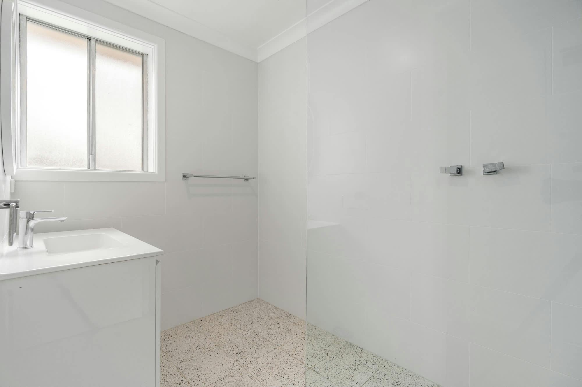 Large bright white bathroom with shower, and vanity