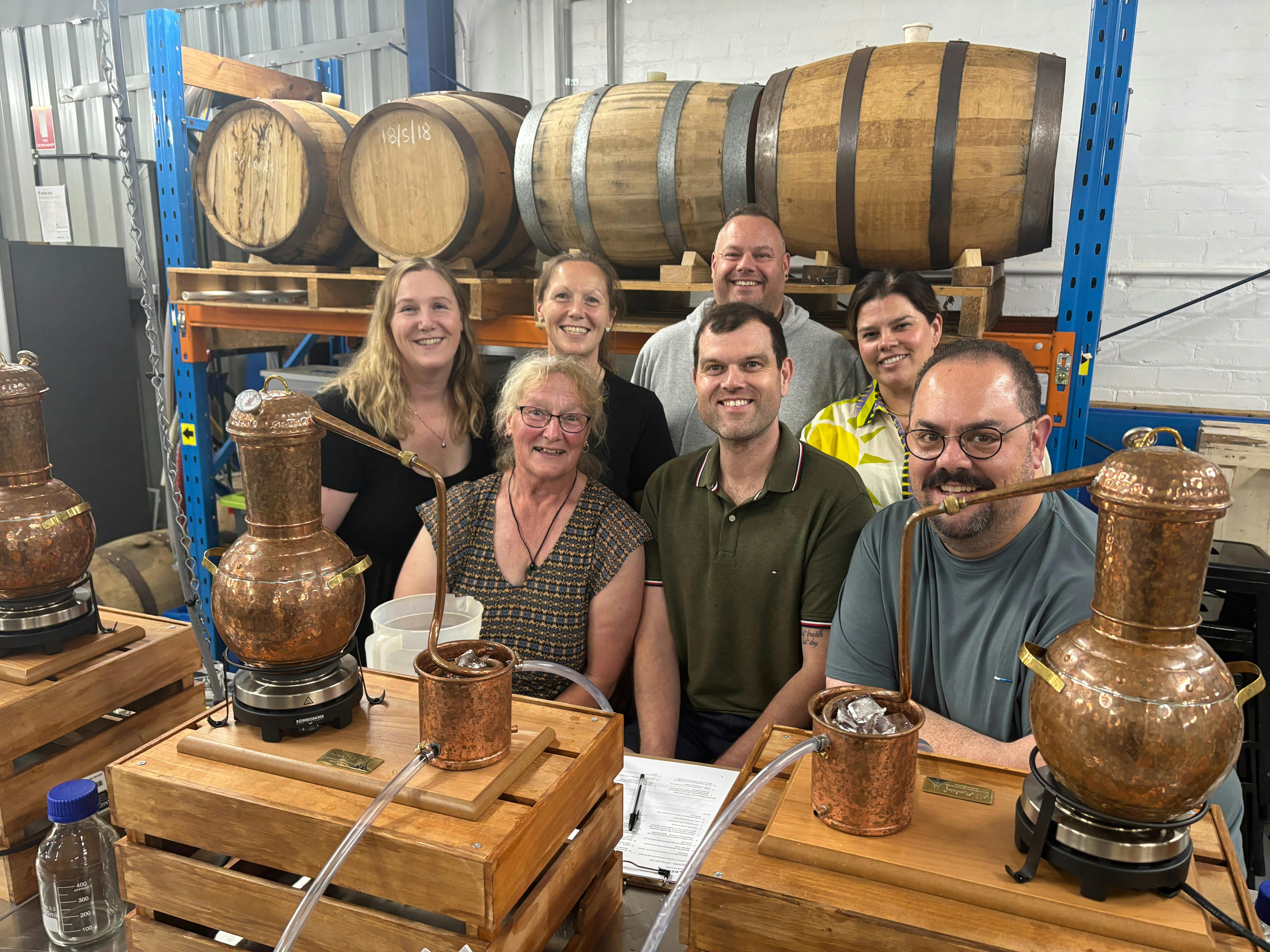 Seven adults in a group behind gin stills