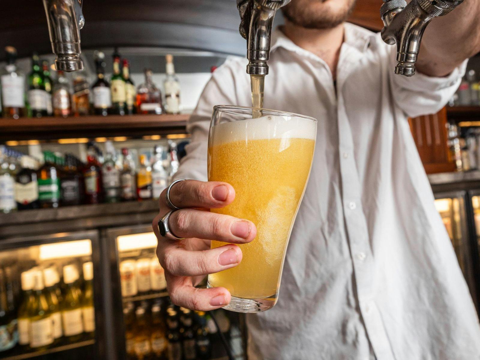 Beer poured out of tap by bartender at The Sussex Hotel.