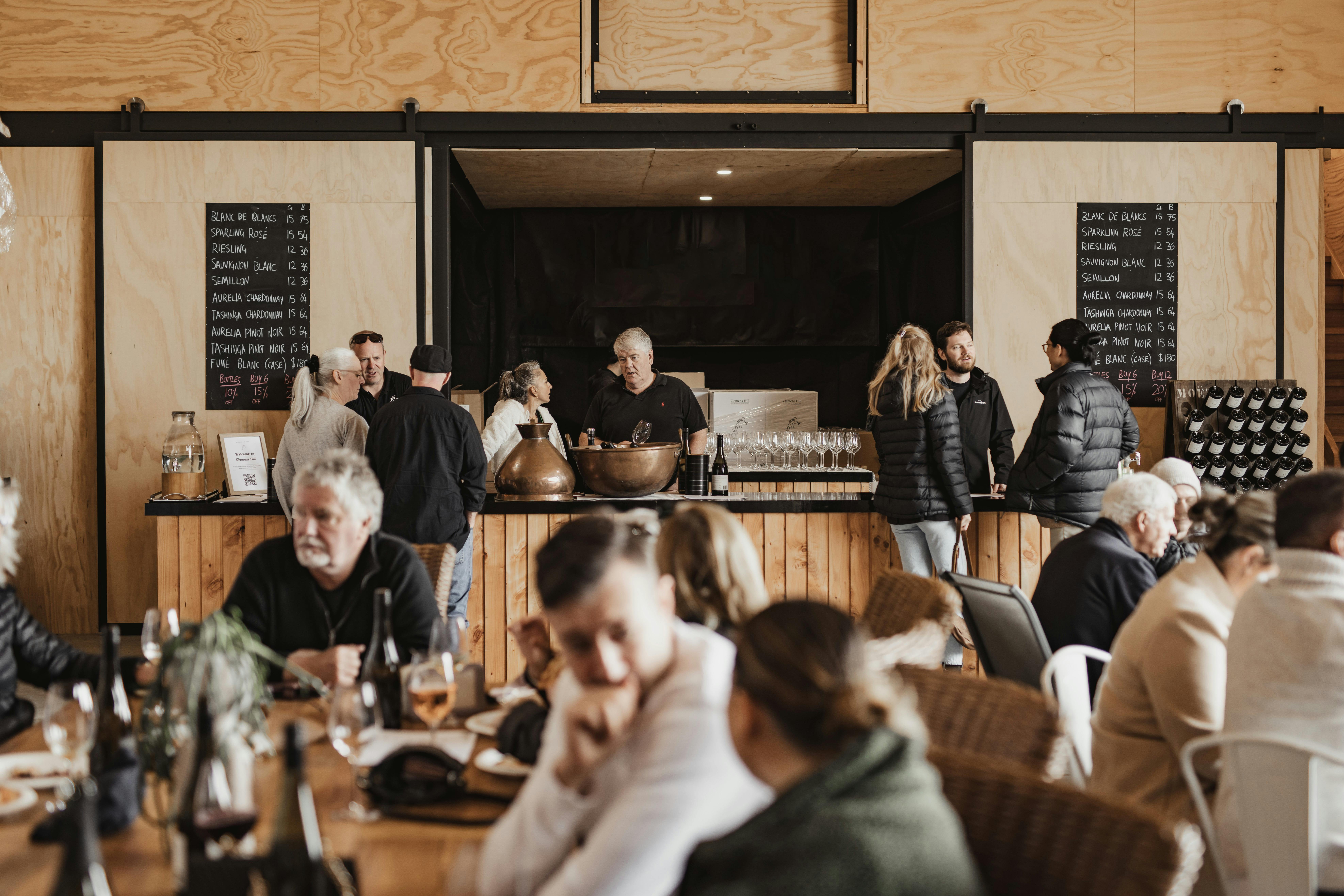 people in vineyard shed drinking wine