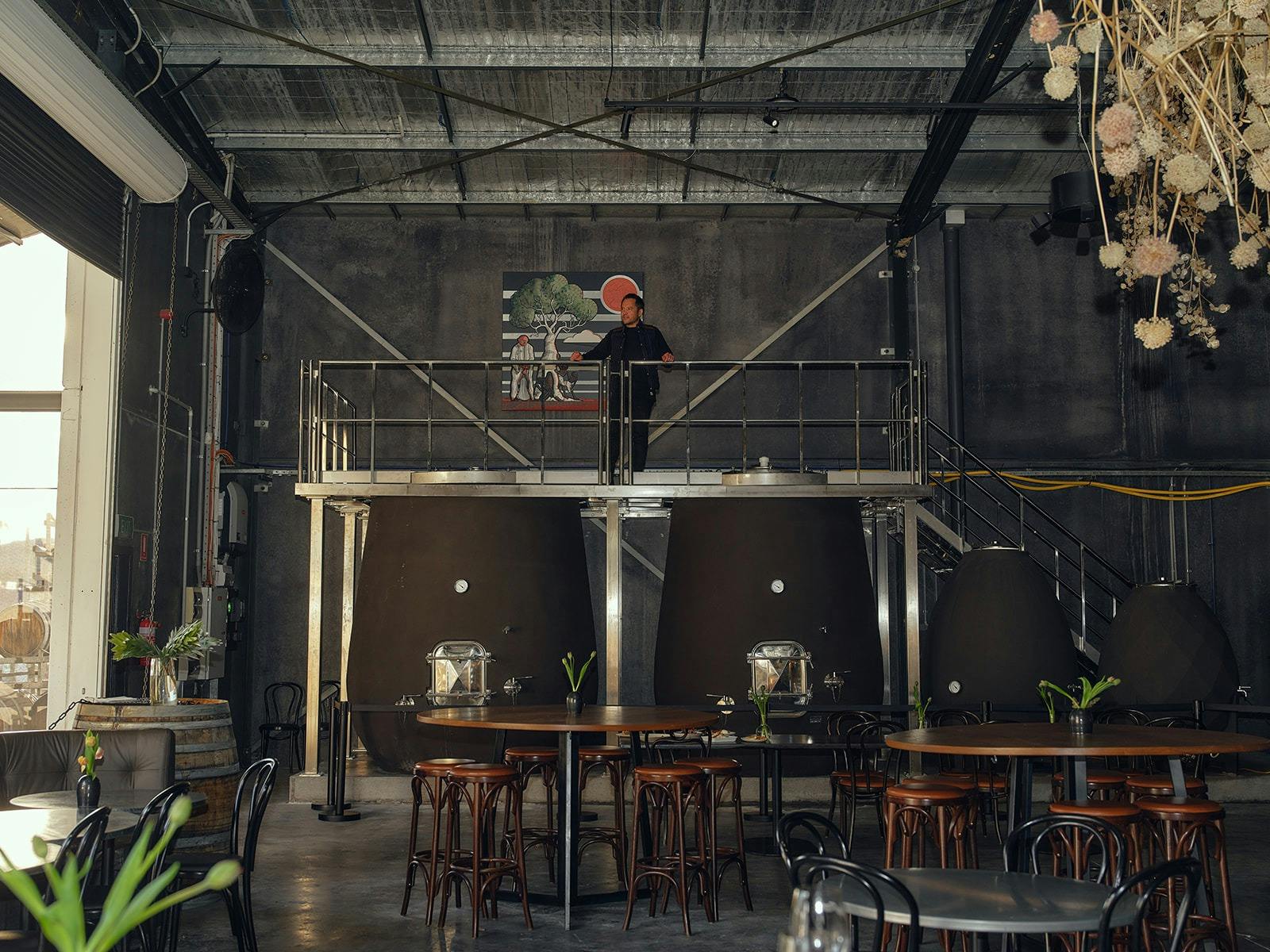 Large concrete tanks at the rear, tall round timber tables with stool seating