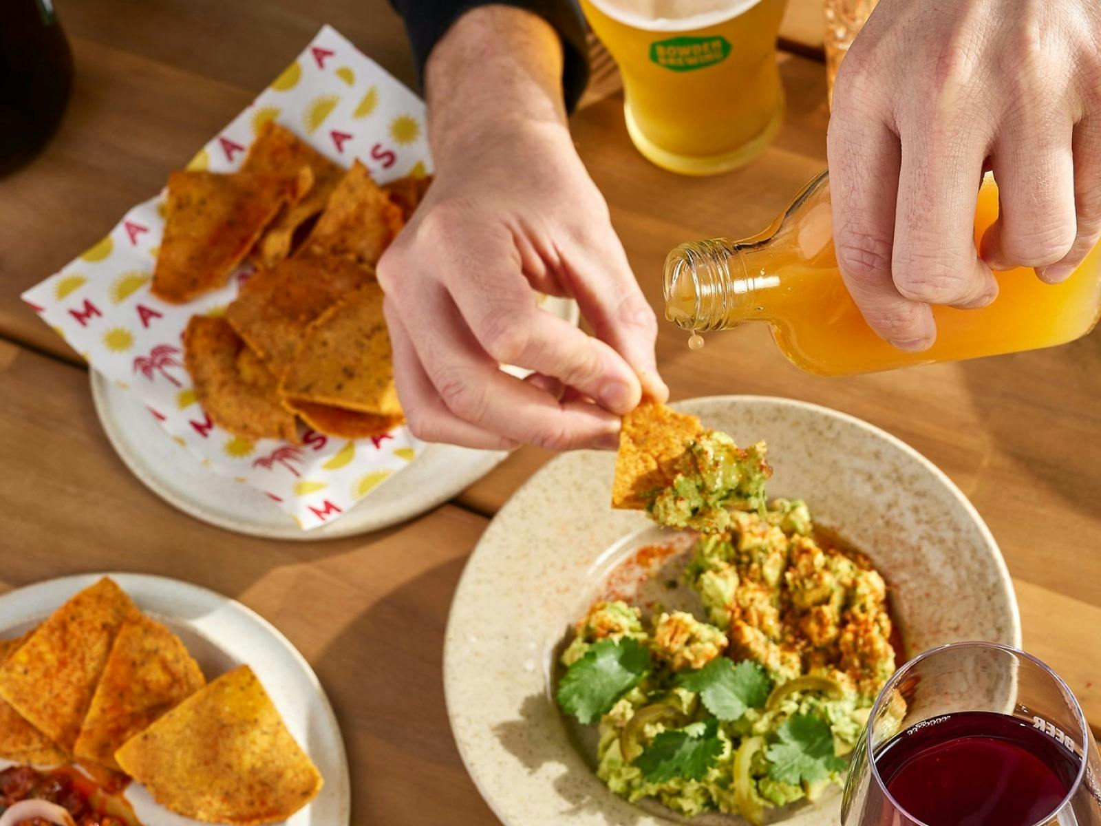 persaon dips a corn chip into guacamole