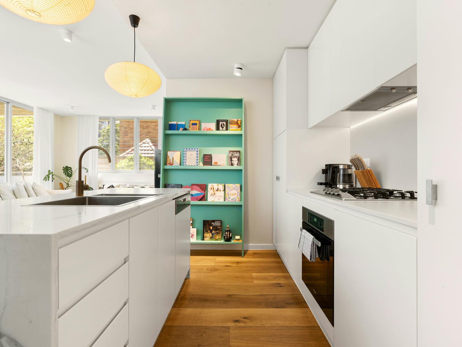 Kitchen with a sleek design, open shelving, and a colorful bookshelf.