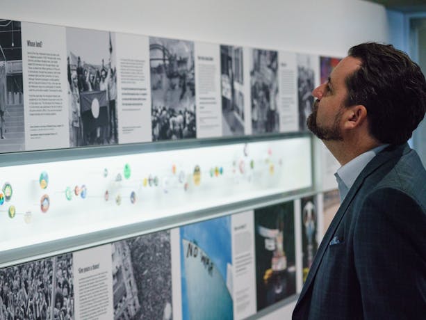 Man looking at exhibition images, text and displayed badges
