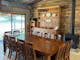 Large timber dining table with chairs in front of a timber buffet and wood heater