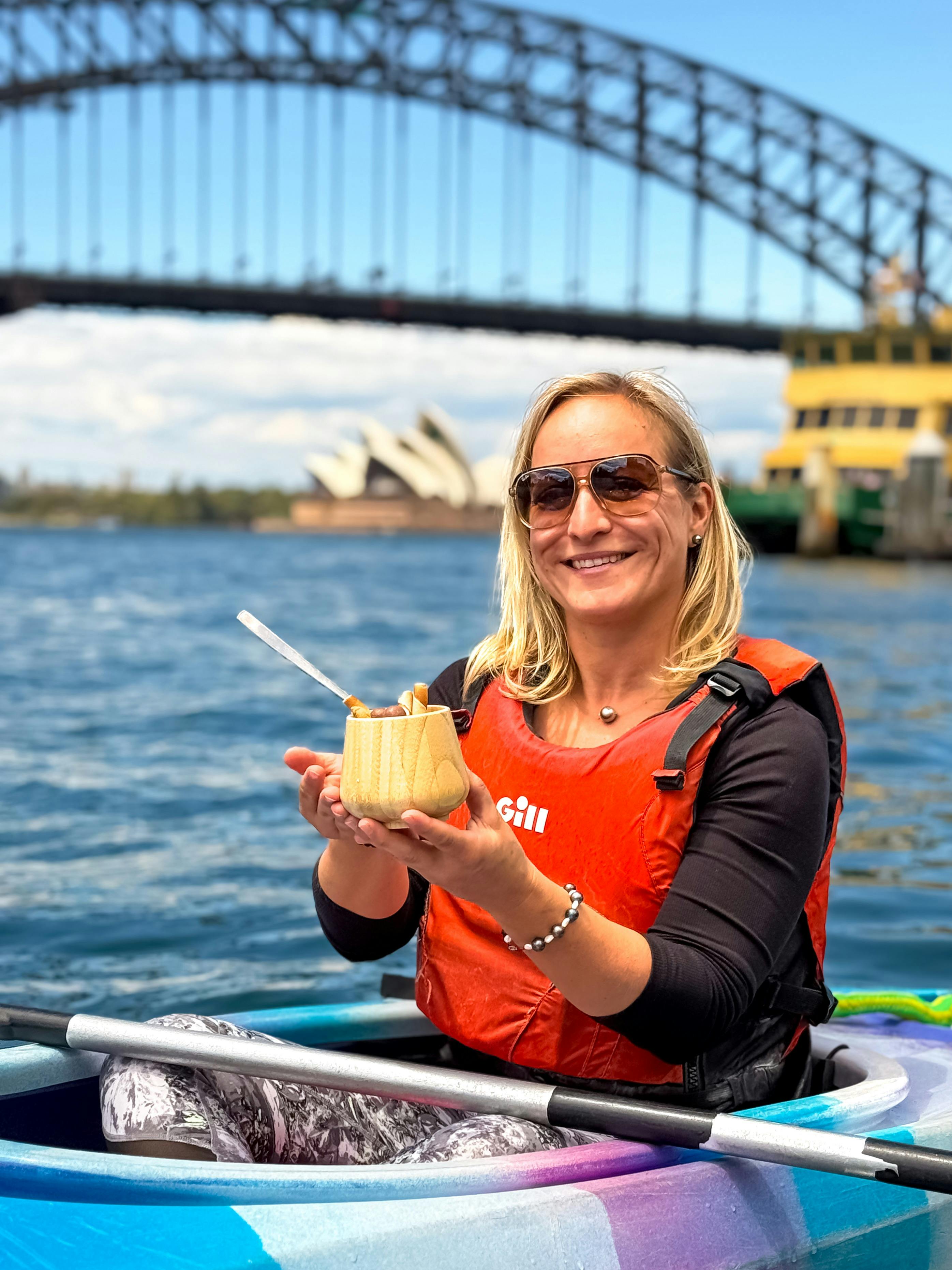 Blonde lady holding her ice cream gelato to camera with sydney harbour bridge and the opera house