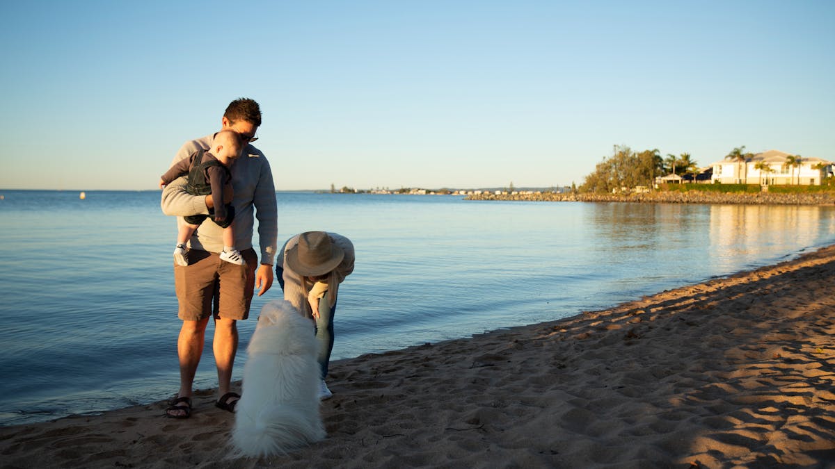 Young family enjoying the dog off-leash area at Raby Bay Foreshore, Redlands Coast — father holding