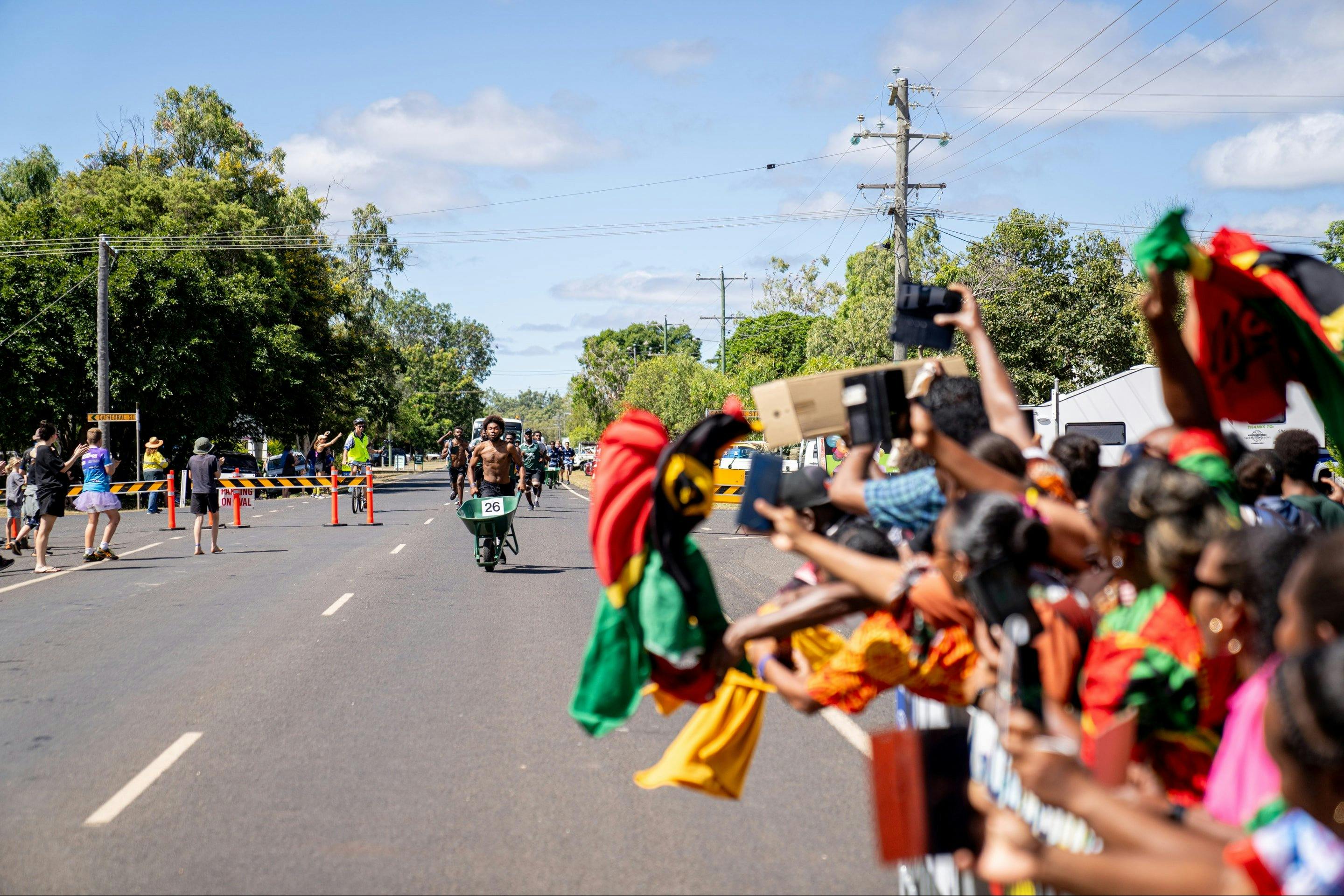 Spectators cheer for an athlete nearing the finish line in The Great Wheelbarrow Race.