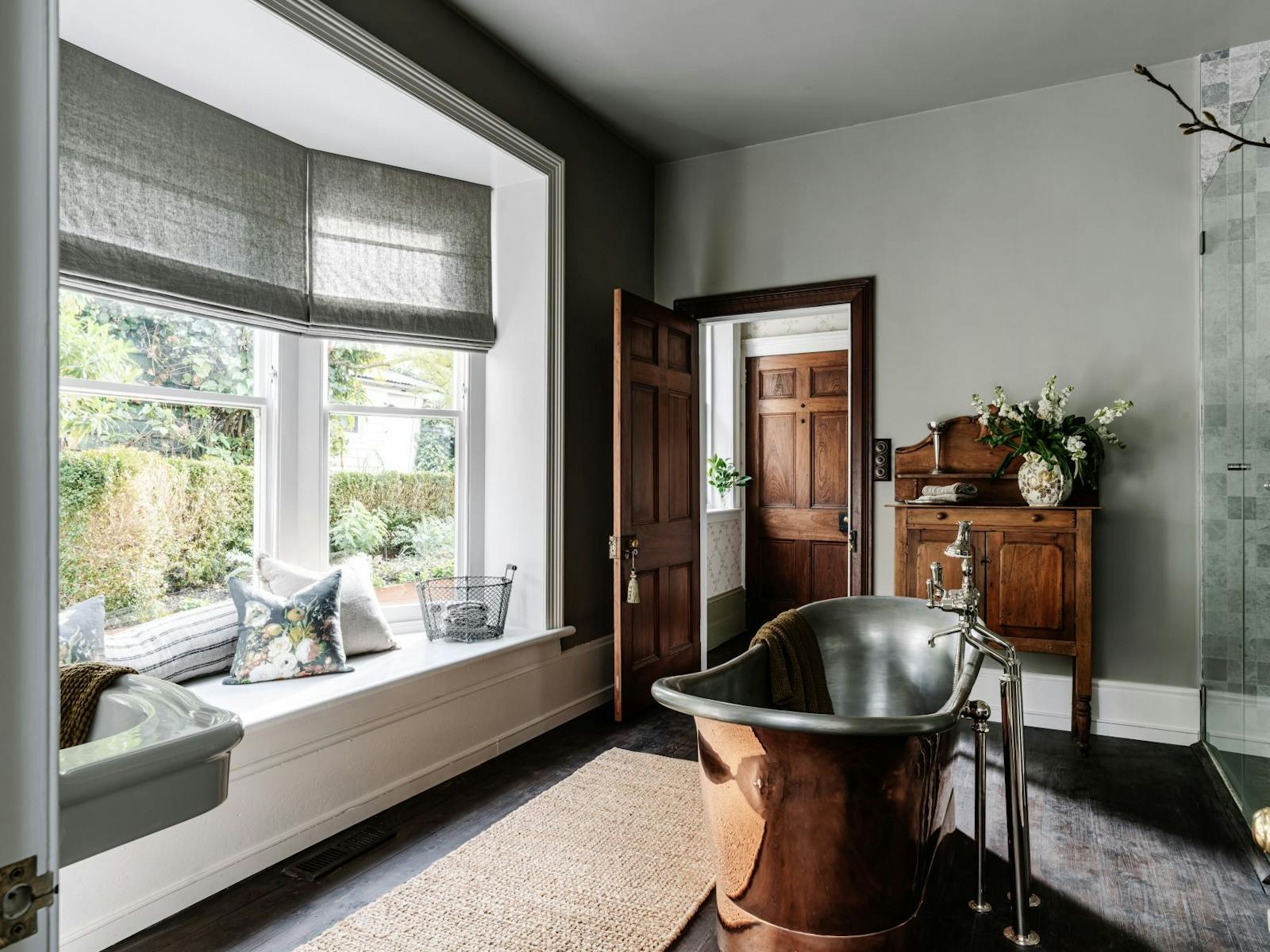 A bathroom with bay windows and a deep free standing copper bath.