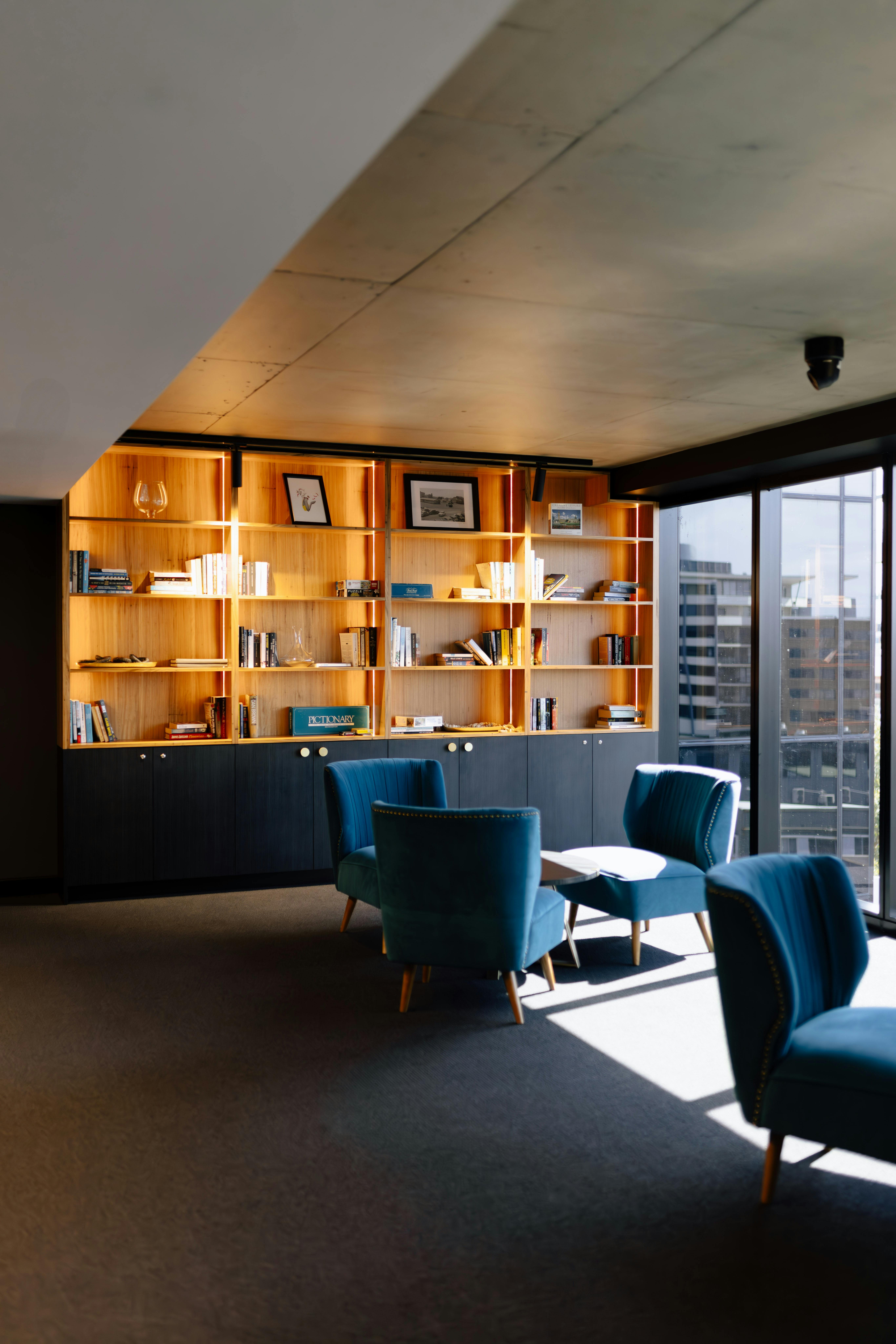Modern lobby seating area with plush chairs, a coffee table, library, and natural light