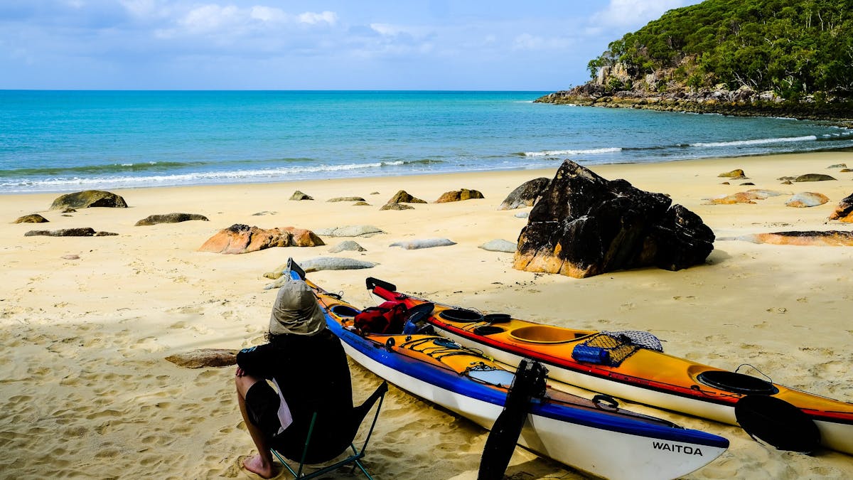 A kayaker contemplates the important things in life while staring out from a remote beach camp