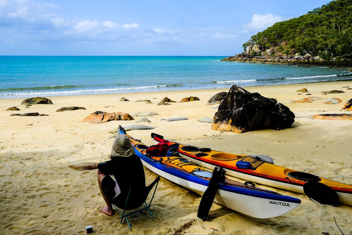 A kayaker contemplates the important things in life while staring out from a remote beach camp