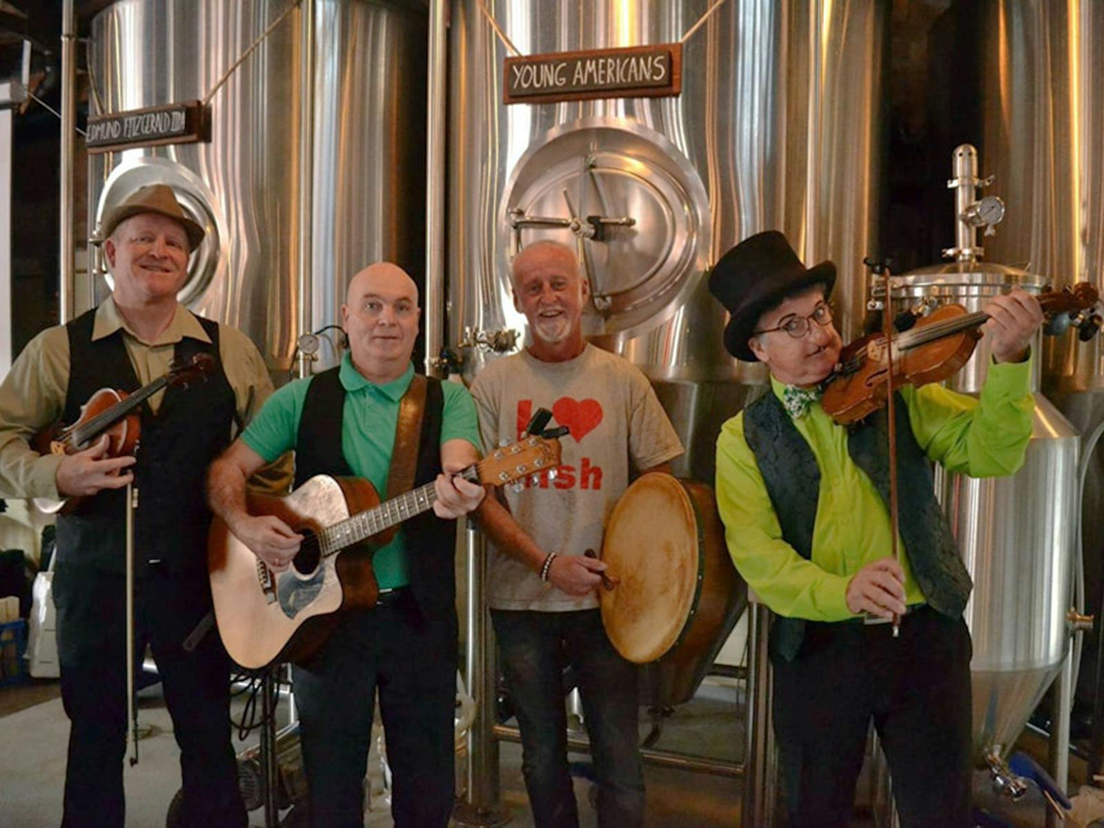 Four members of an Irish band dressed in green and posing with their instruments
