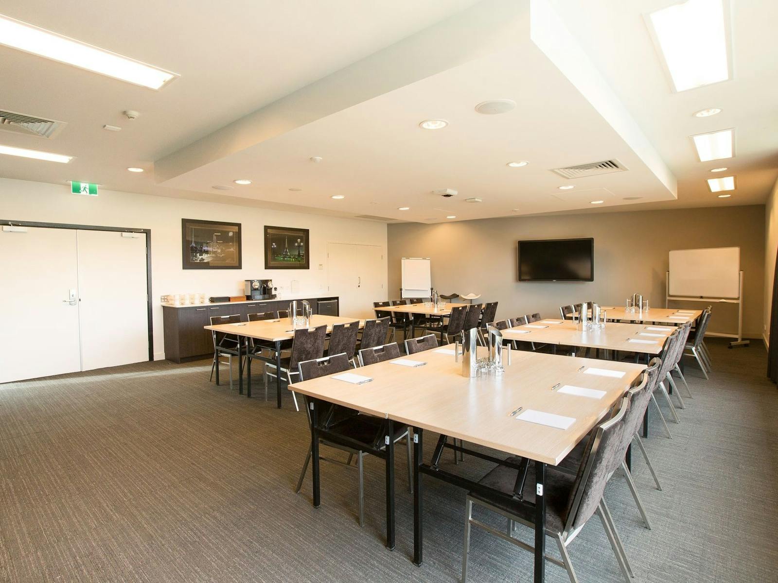 A wide shot of our Conference Room, with a tea and coffee station, tables, chairs and AV equipment