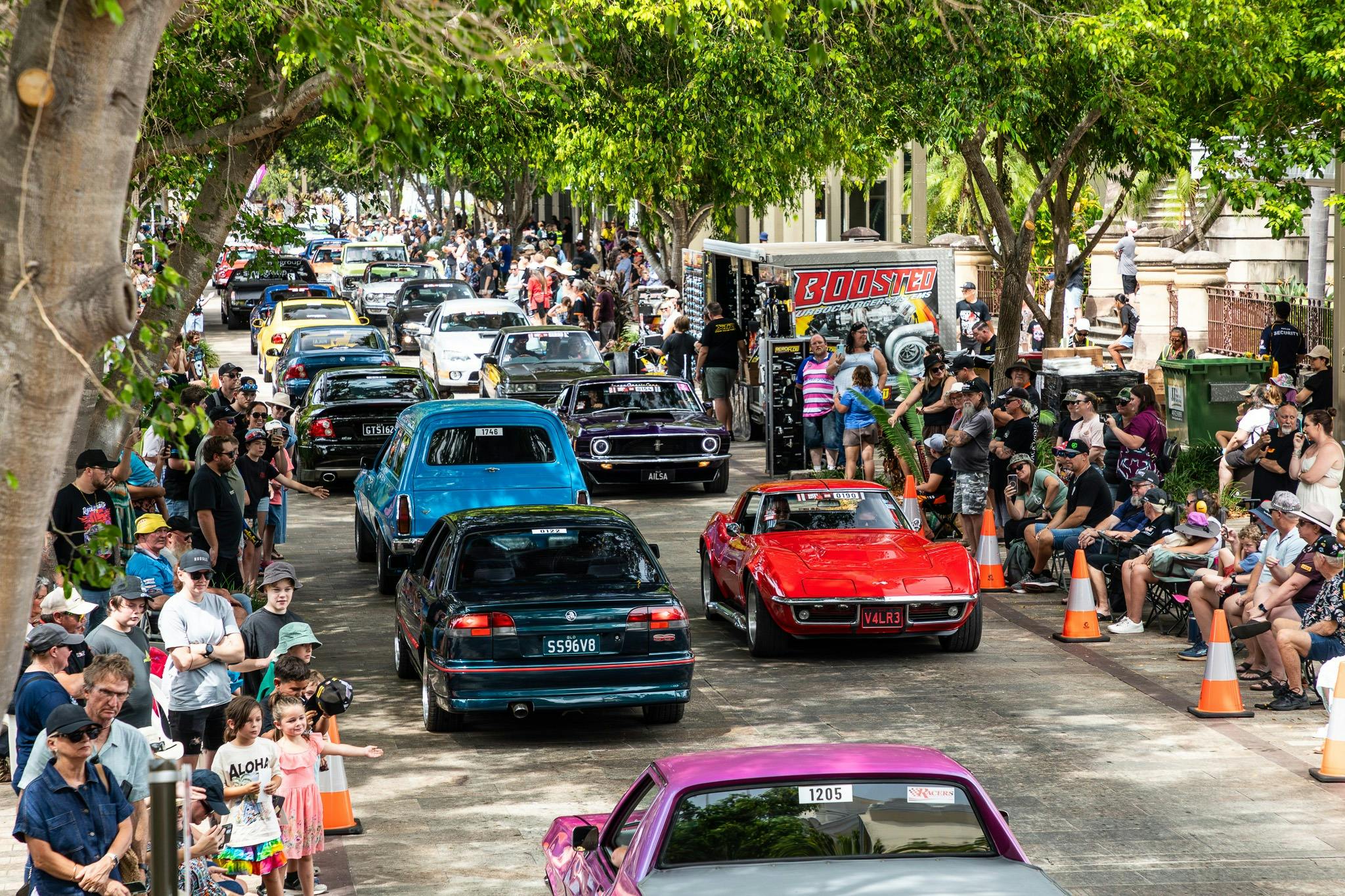 Classic and custom cars driving past crowds on a city street during Rockynats.