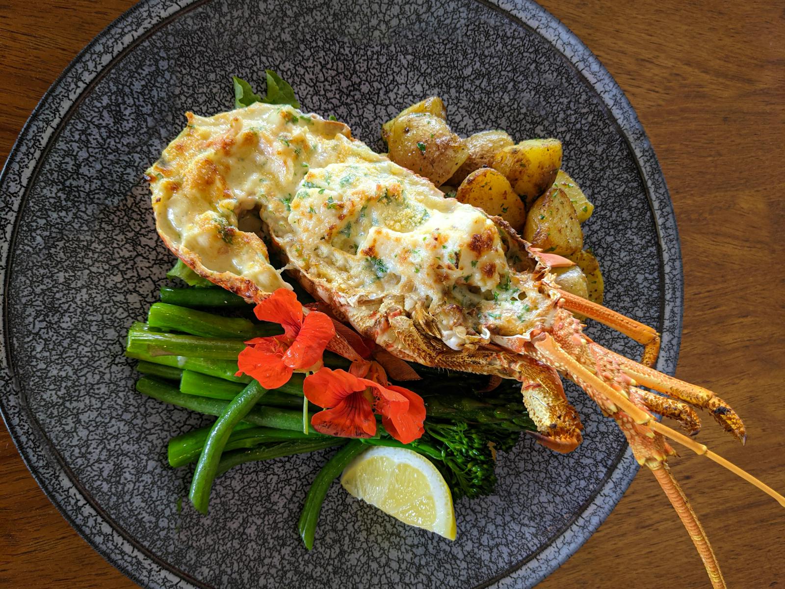 A dish featuring Tasmanian Southern Rock Lobster with mornay sauce and accompanying sides.