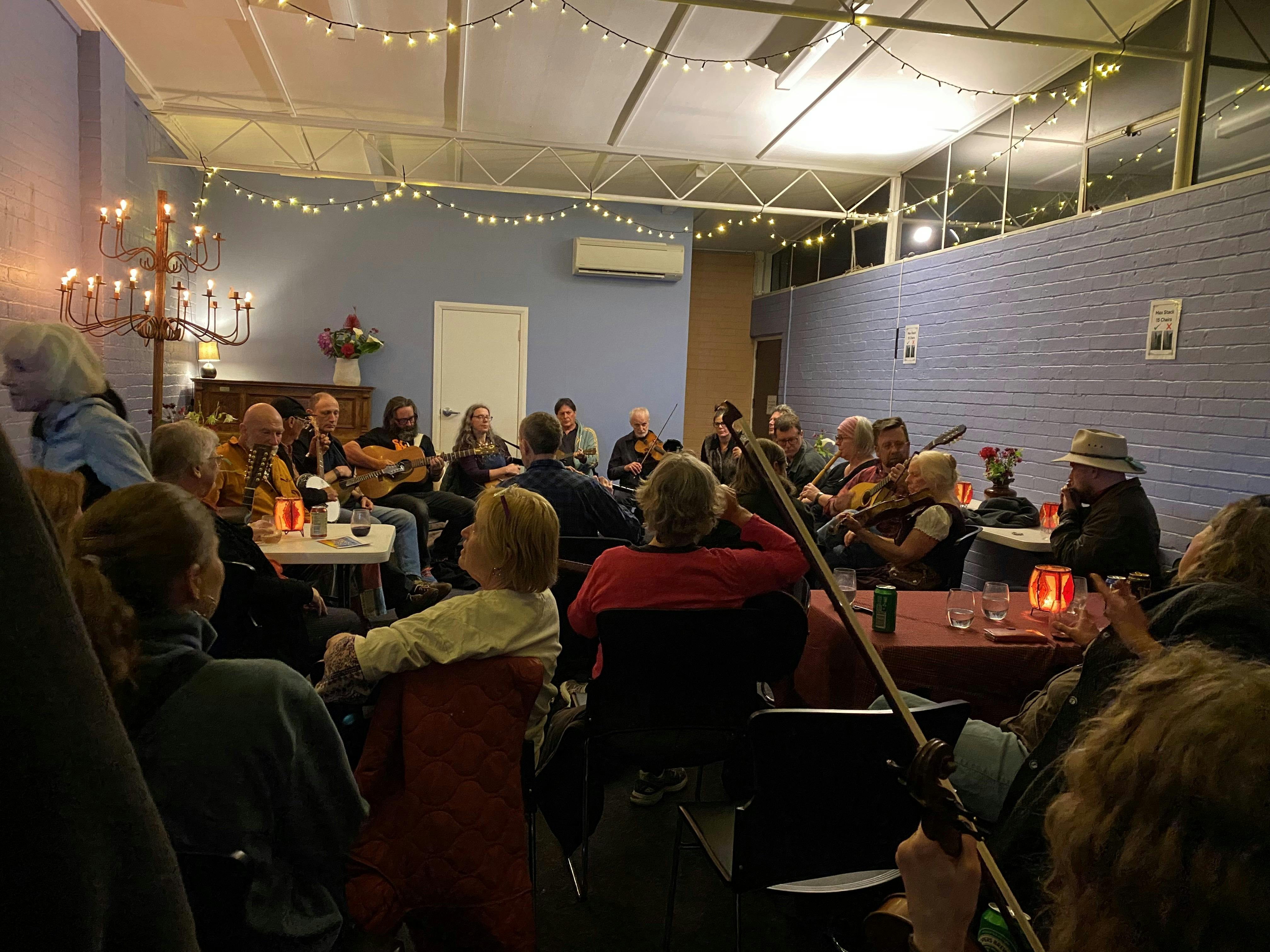 Musicians playing acoustic instruments together in a warmly lit Sheffield festival venue.