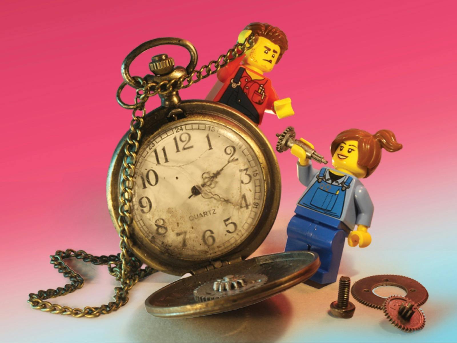 Two LEGO minifigures interact with an open, worn pocket watch, against a pink‑to‑blue background