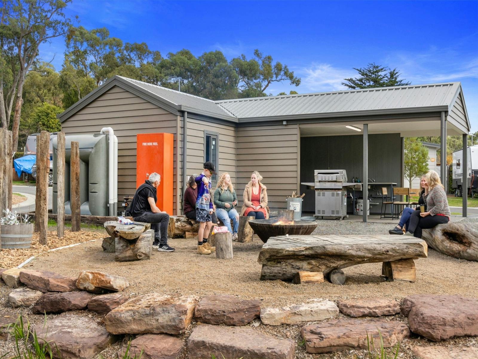 Family sitting around firepit at Lilydale Pine Hill Caravan Park