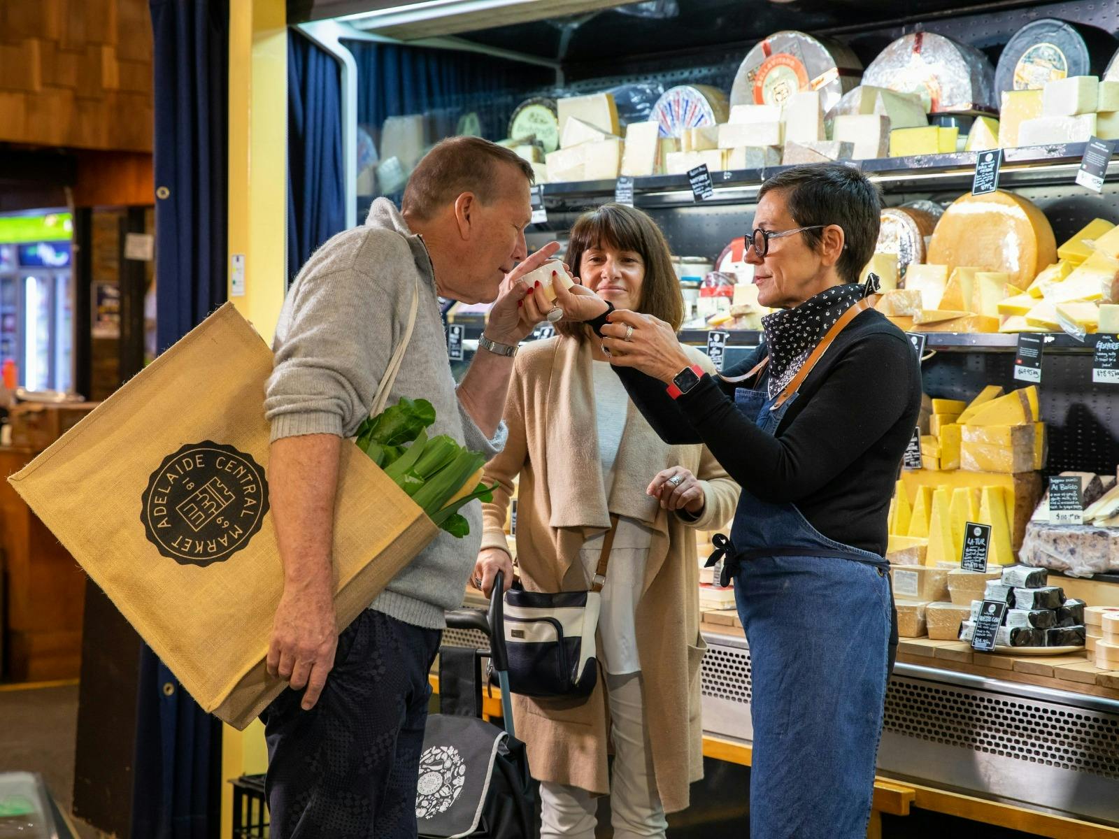 Woman holding cheese to mans nose as he smells it