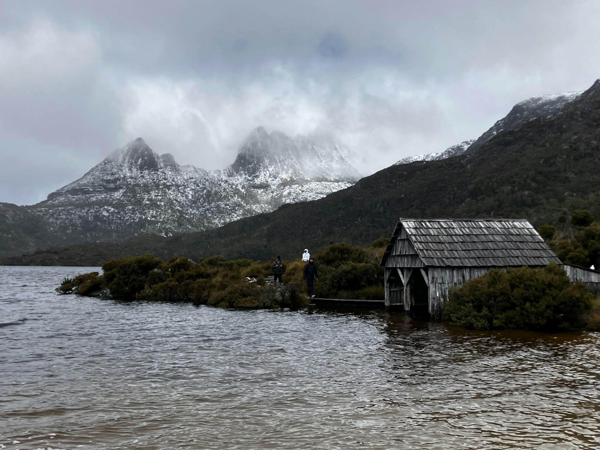 The iconic boatshed at Dove Lake, framed by the rugged, snow-covered peaks of Cradle Mountain.