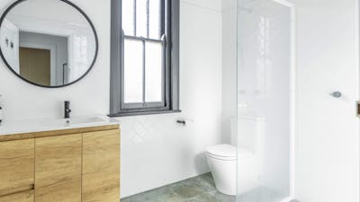 Bathroom with sink, mirror, toilet, window and shower.