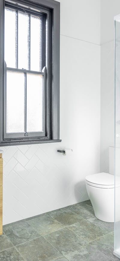 Bathroom with sink, mirror, toilet, window and shower.