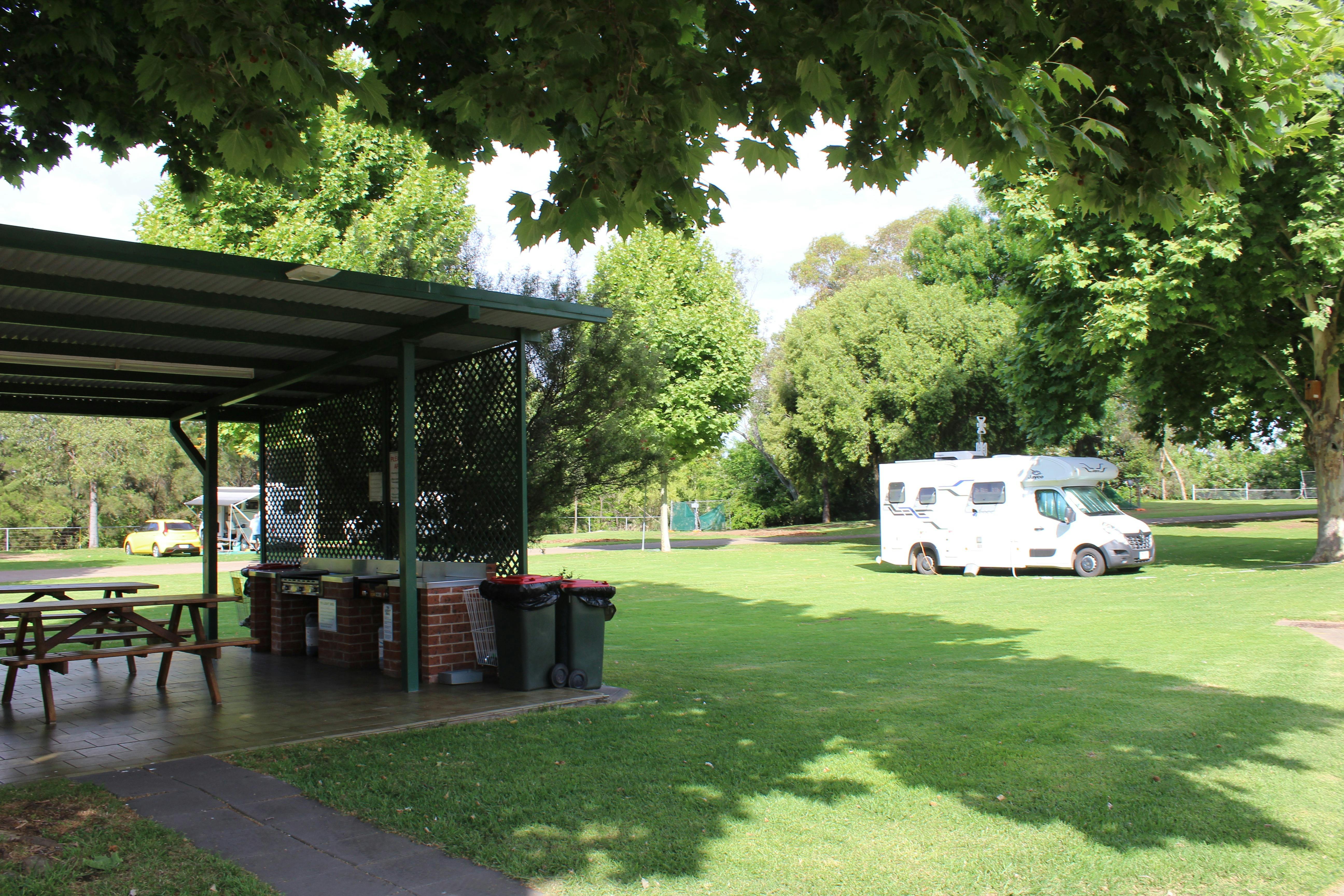 쓰레기통이 있는 바비큐 공간 넓은 잔디밭과 배경에 캐러밴이 보입니다.