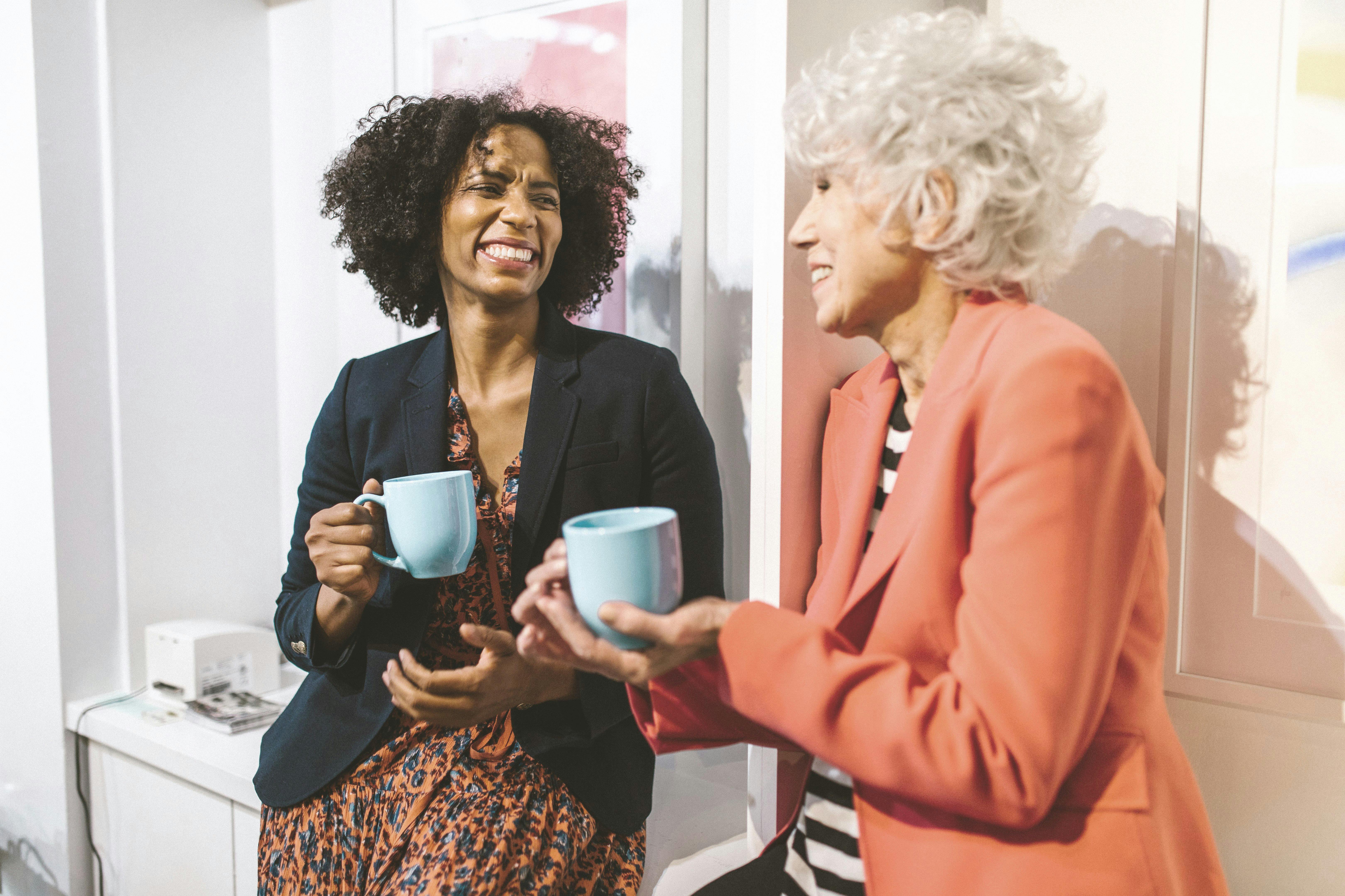 two people chatting in a gallery space with a cup of coffee