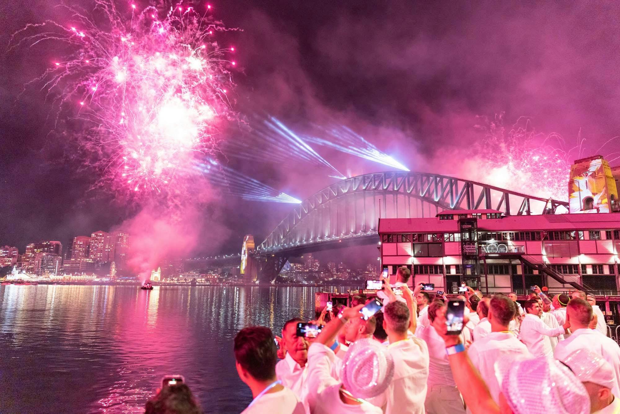 Fireworks over Sydney Harbour Bridge with guests watching from Walsh Bay.