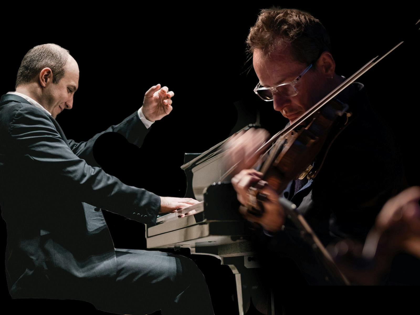 A man playing on a Piano and another playing the Violin