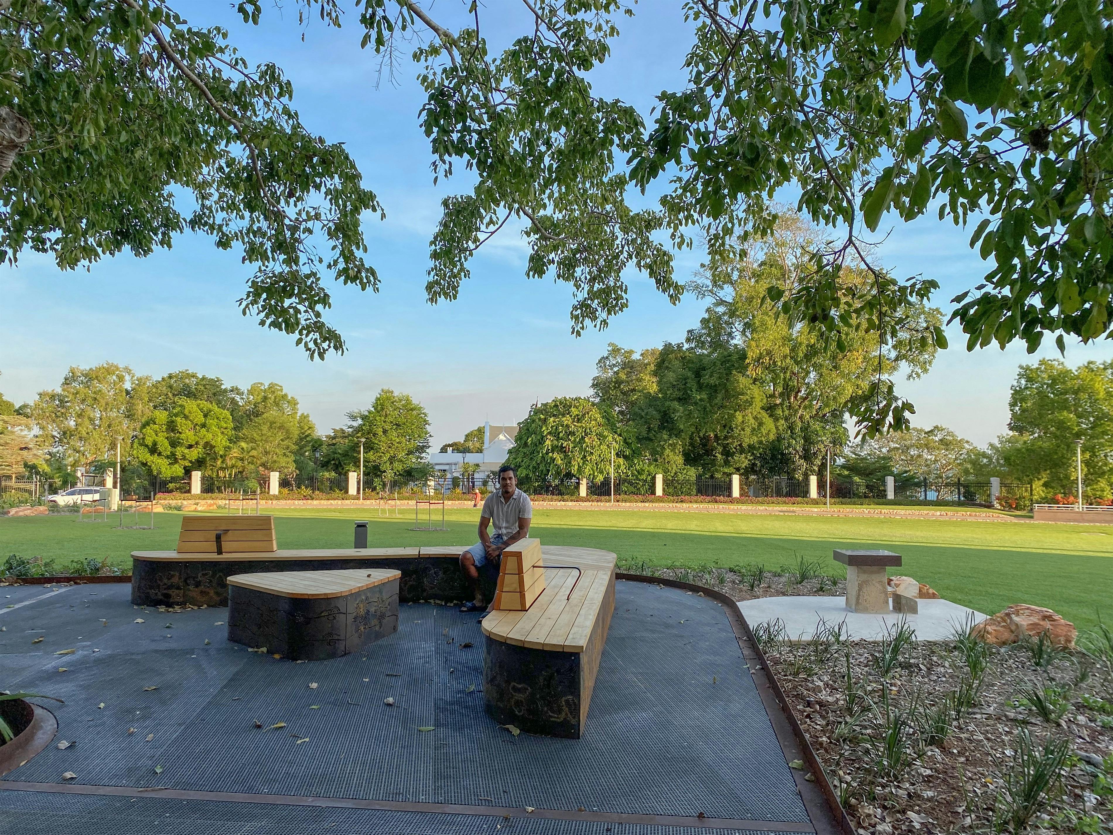 Larrakia/Mayalli artist Keelan Fejo on the bench seating at Liberty Square that features his artwork