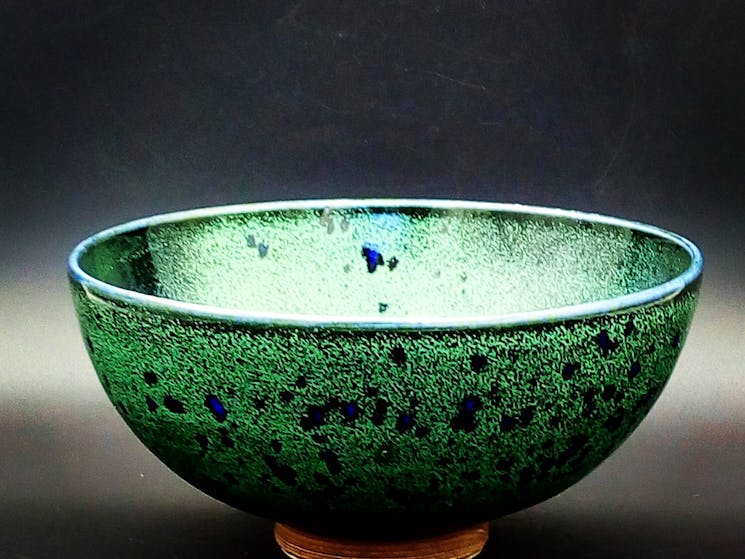 Bowl, made on the potters wheel  and finished in a green glaze with glassy blue spots.